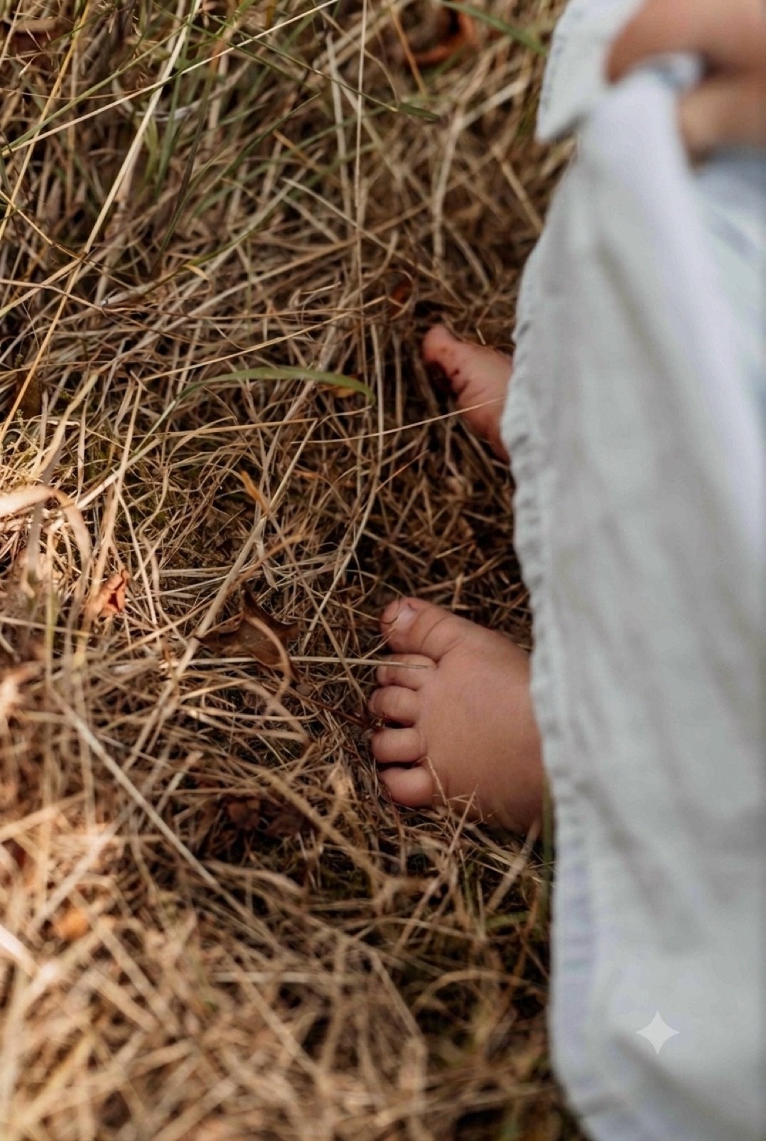 Nackte Kinderfüße stehen im trockenen Gras