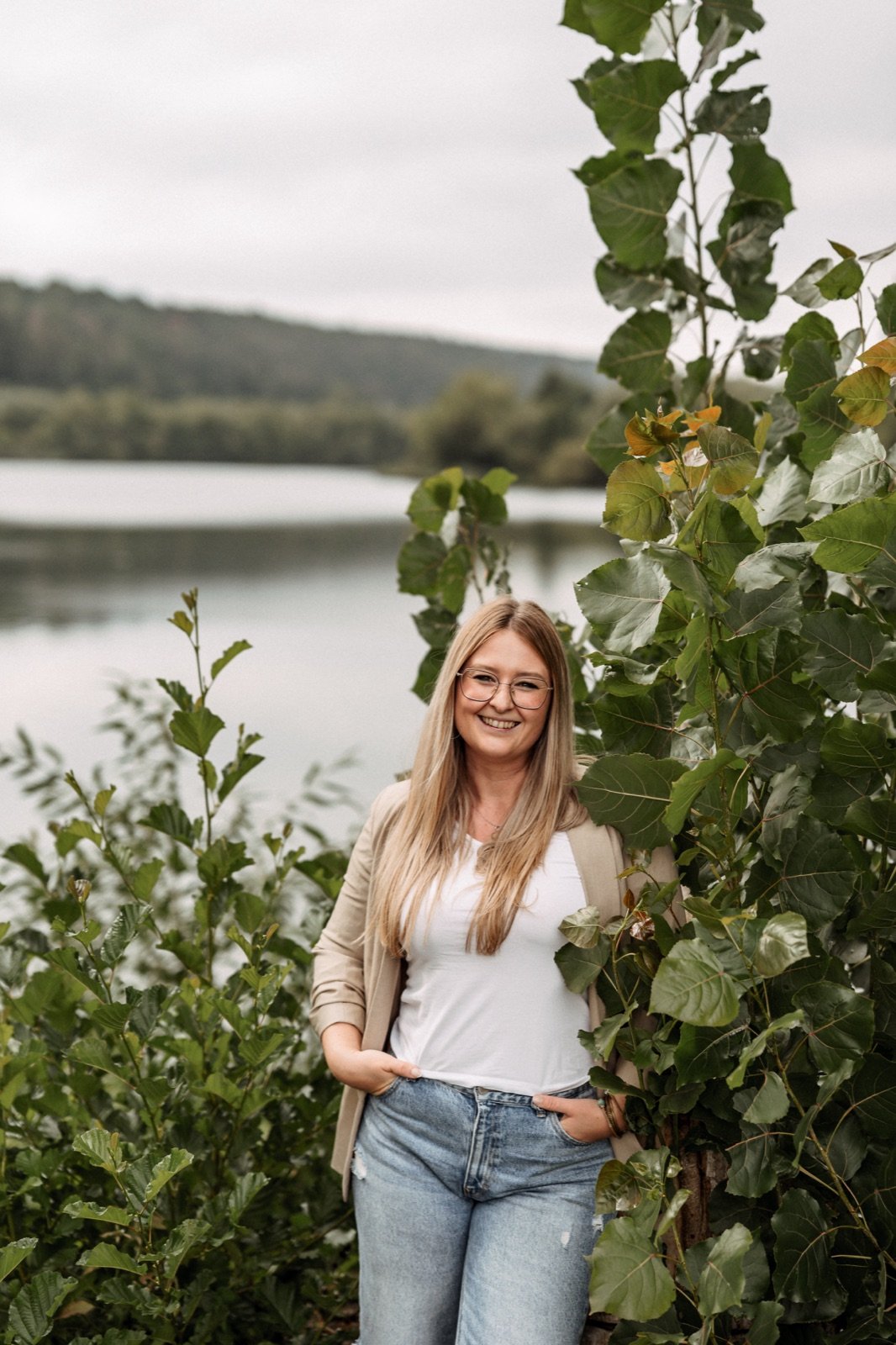 Sarah Meister lächelt in die Kamera, hinter ihr ein See