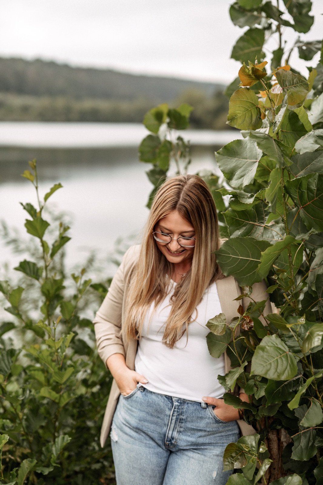 Sarah Meister im Freien an einem See, sie schaut lächelnd nach unten